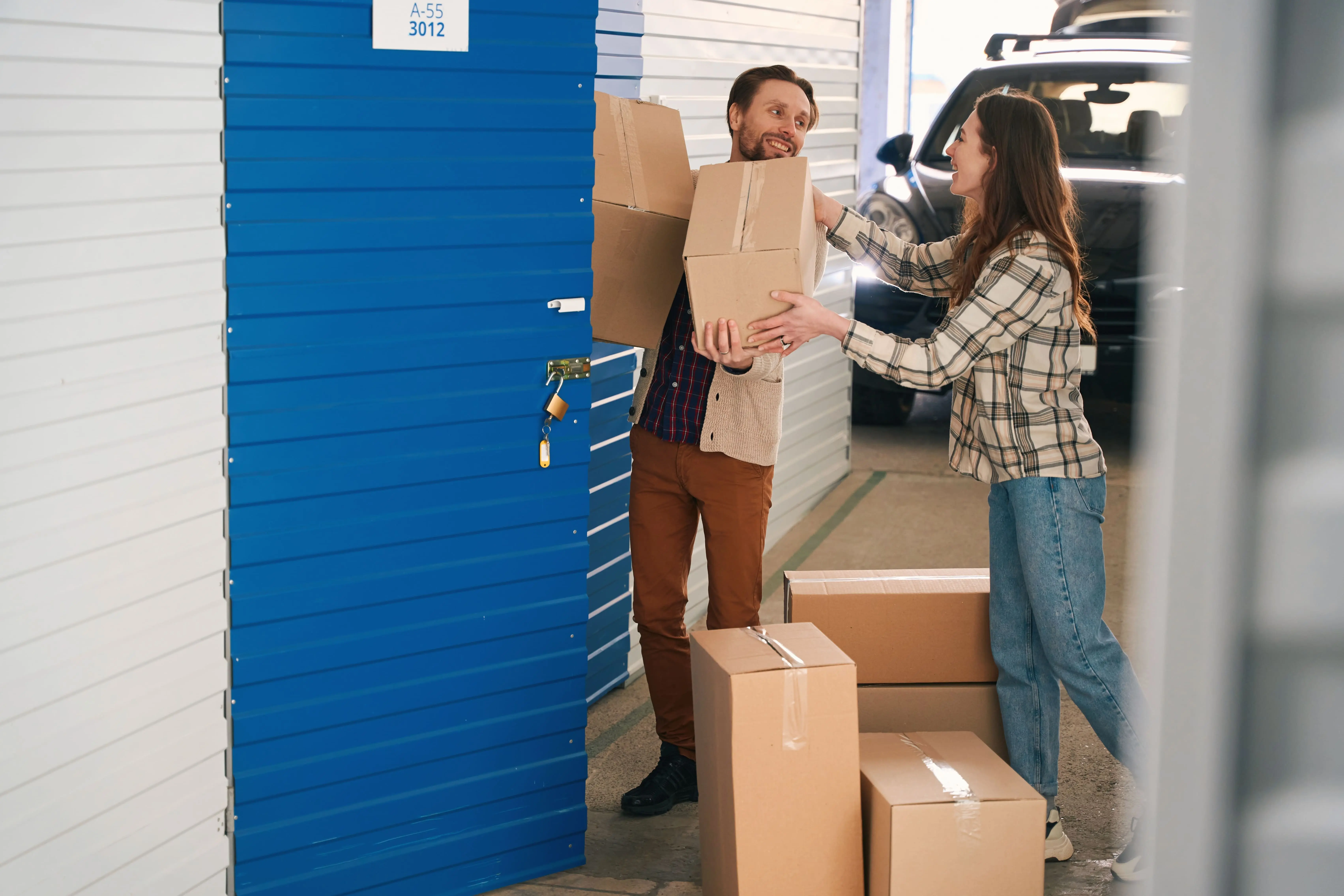 Young couple with big cardboard boxes into warehouse with self storage unit